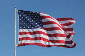 The American Flag in the wind at the top of a flagpole